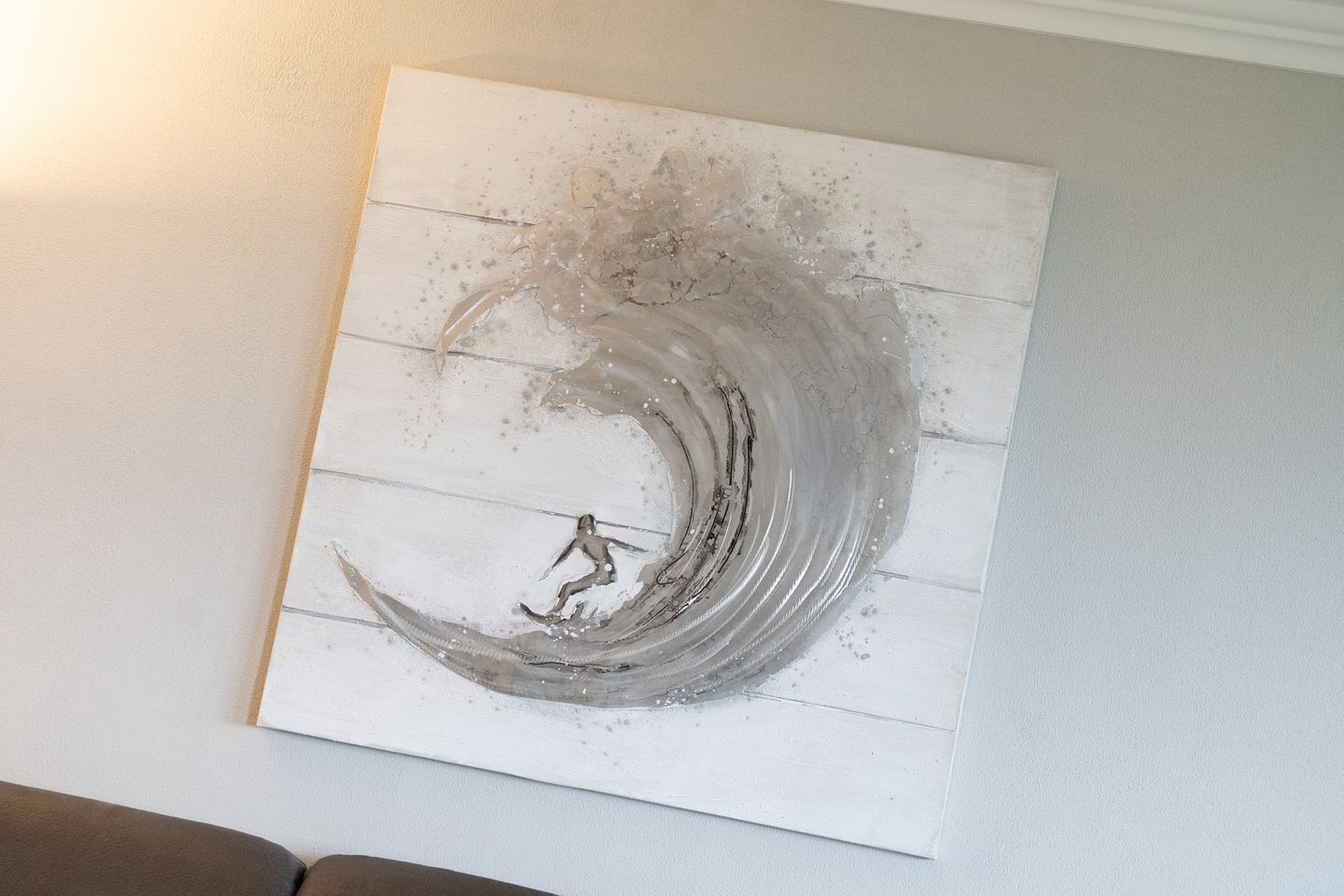 Una pared con una obra de arte texturizada que muestra una ola y una figura.