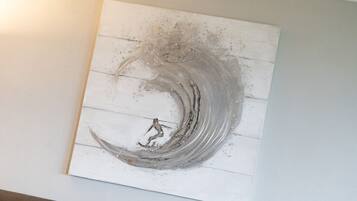 Una pared con una obra de arte texturizada que muestra una ola y una figura.