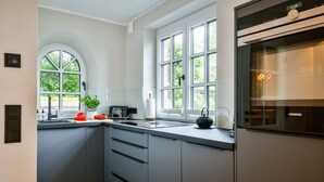 A modern kitchen with grey cabinets, a black kettle, and a Siemens oven.