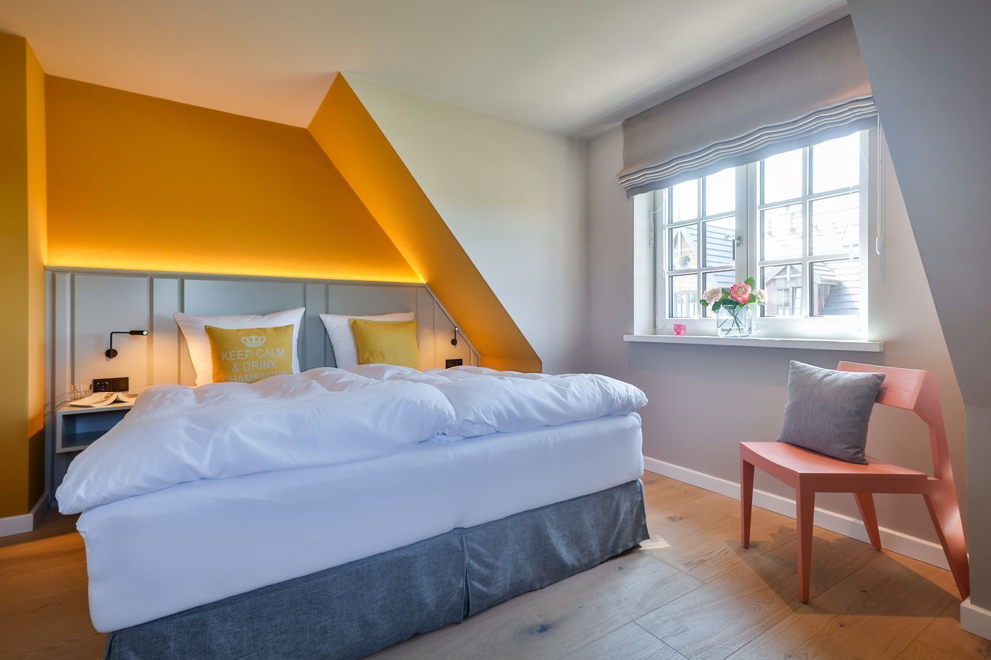 Un dormitorio moderno con una cama grande, una mesita de noche, una silla y una ventana con vistas a edificios.