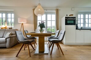 Una cocina moderna con armarios blancos, una mesa de comedor de madera y dos sillas grises.