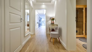 A hallway with wooden flooring, white walls, and a chair. There is a door on the left and a wooden door on the right. - Modern apartment for two people in a location absolutely close to the beach - House (Hörnum (Sylt))