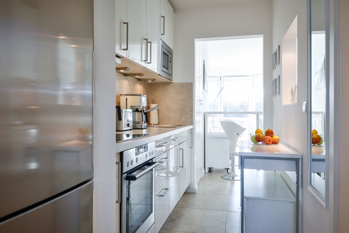 A modern kitchen with white cabinetry, stainless steel appliances, and a large window providing natural light.