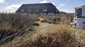 Un bâtiment doté d’un toit en pente, de nombreuses fenêtres et d’un chemin menant à l’entrée.