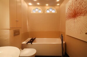 A bathroom with a bathtub, toilet, and a wall-mounted sink.