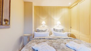 Una habitación de hotel con una cama grande, dos lámparas de noche, una mesita de noche y un armario.