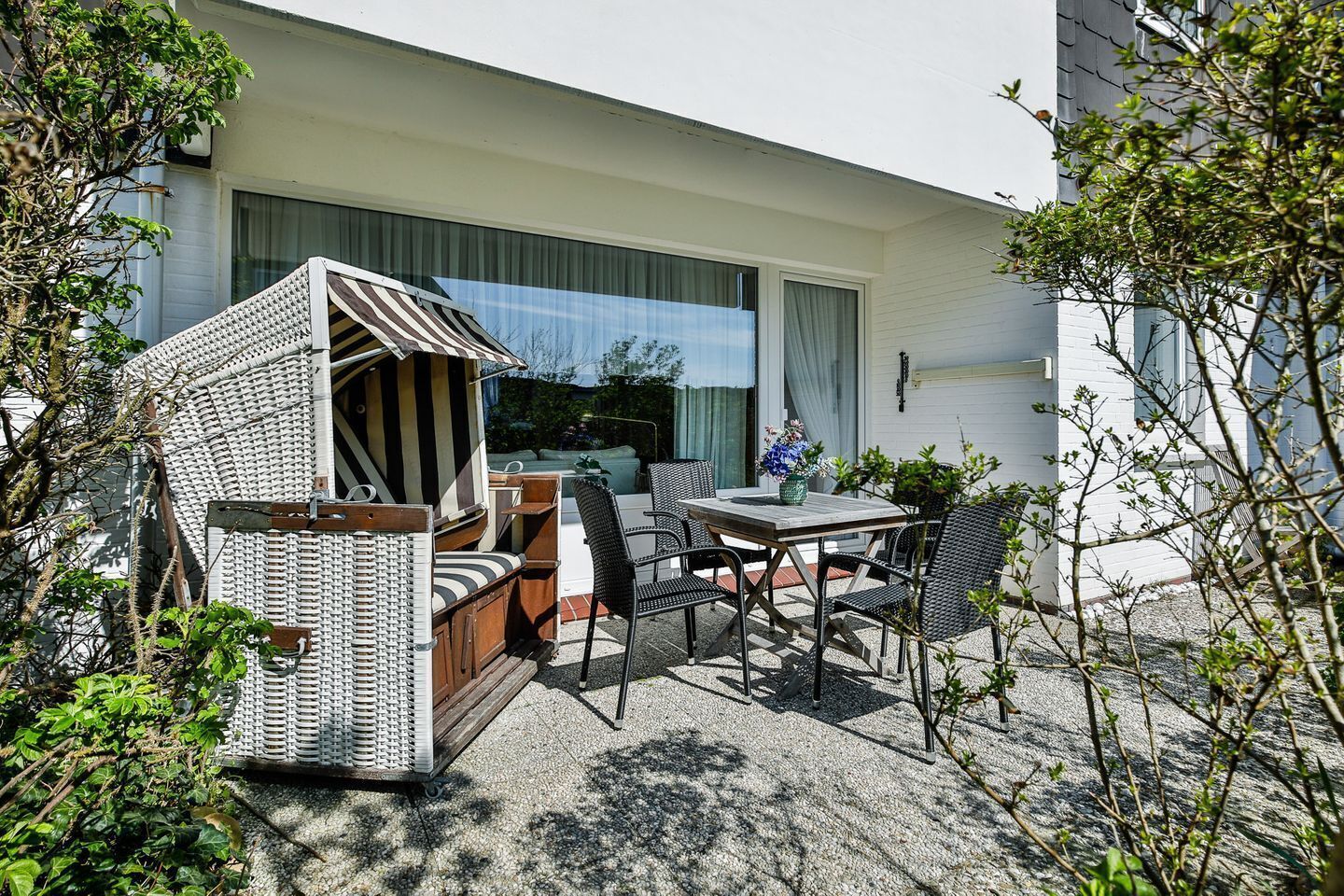 Un patio con una zona de estar exterior a rayas, una mesa y sillas.