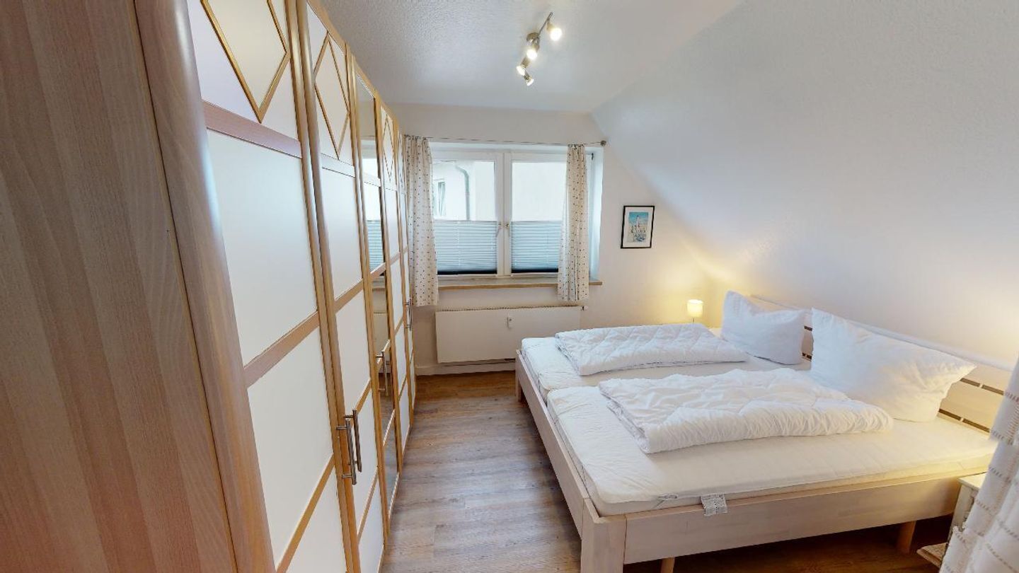 A bedroom with a bed, a window, and a wardrobe.