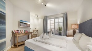 Une chambre à coucher avec un lit, un bureau avec des livres, une chaise, une fenêtre avec des rideaux et une lampe.