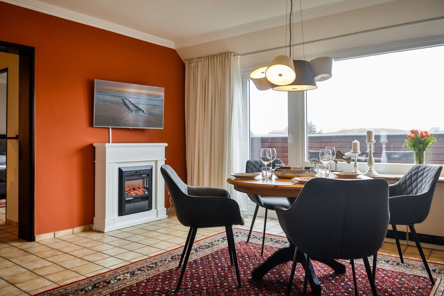 A dining area with a fireplace, a painting, and a view of the city.
