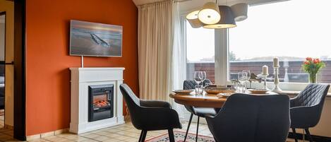 A dining area with a fireplace, a painting, and a view of the city.
