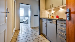 Una cocina moderna con armarios grises, lavavajillas y puerta de madera.