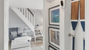 Uma escadaria leva a um quarto com uma cama, um criado-mudo e um abajur.