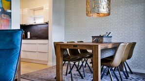Un comedor con mesa de madera, sillas negras y alfombra estampada.