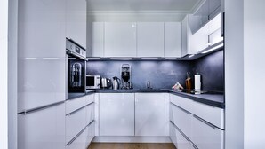 Una cocina moderna con armarios blancos, electrodomésticos de acero inoxidable y piso de madera.