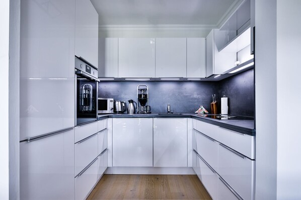 Una cocina moderna con armarios blancos, electrodomésticos de acero inoxidable y piso de madera.