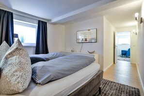 Une chambre à coucher moderne avec un lit, une table de chevet et un téléviseur fixé au mur.