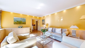 A living room with a sofa, armchairs, a coffee table, and a painting on the wall.