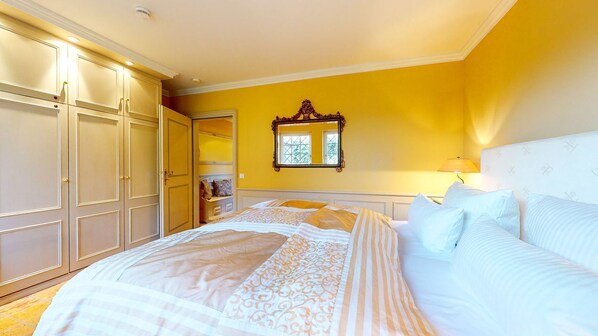 A bedroom with a bed, a wardrobe, a mirror, and a lamp.
