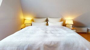 Une chambre à coucher avec un grand lit, deux lampes de chevet et un radiateur.