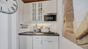 A kitchen with white cabinets, a stainless steel oven, and a clock on the wall. - Fischer - Praktisches Appartement in Strandnaher Lage Inmitten Einer Heidelandschaft (Hörnum (Sylt))