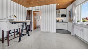 A modern kitchen with white cabinets, a microwave, and a window with a view. - Fischer - Praktisches Appartement in Strandnaher Lage Inmitten Einer Heidelandschaft (Hörnum (Sylt))