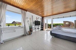 Ein modernes Schlafzimmer mit einem großen Bett, einem Fernseher und Blick ins Freie.