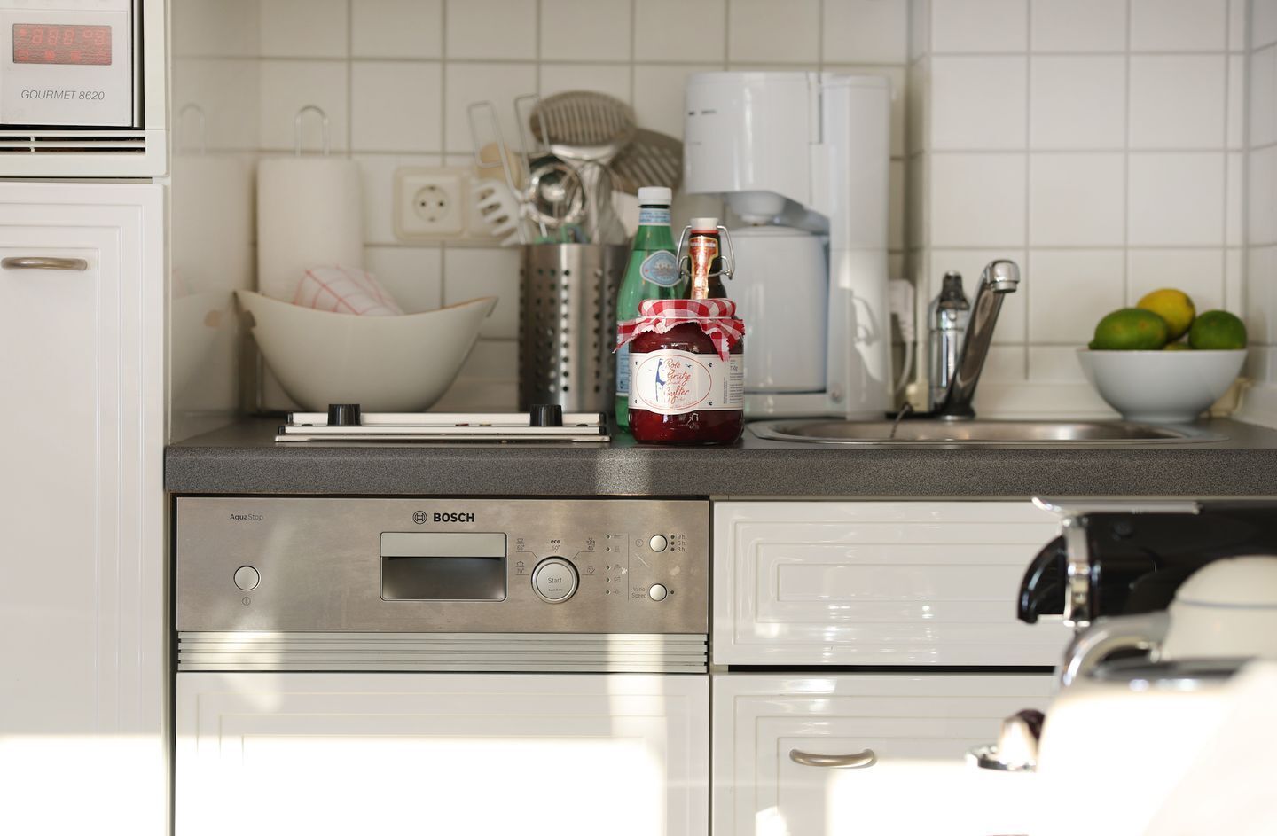 Una cocina moderna con lavavajillas Bosch, una cafetera y un bol de fruta sobre la encimera.
