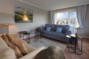 Ein Wohnzimmer mit einer Couch, zwei Beistelltischen, einem Couchtisch und einem Bild an der Wand.