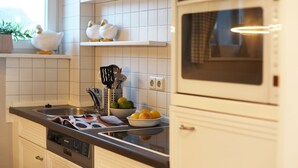 Una cucina moderna con mobili bianchi, forno integrato e lavello in acciaio inossidabile.