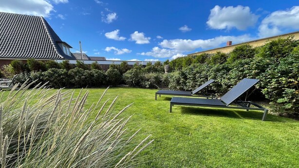 A grassy backyard with two lounge chairs and a solar panel. - Bright vacation apartment in a central location close to the beach in Westerland. - Beach villa (Sylt)