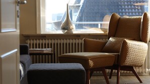 A cozy room with a leather armchair, a small side table, and a radiator. - Bright vacation apartment in a central location close to the beach in Westerland. - Beach villa (Sylt)