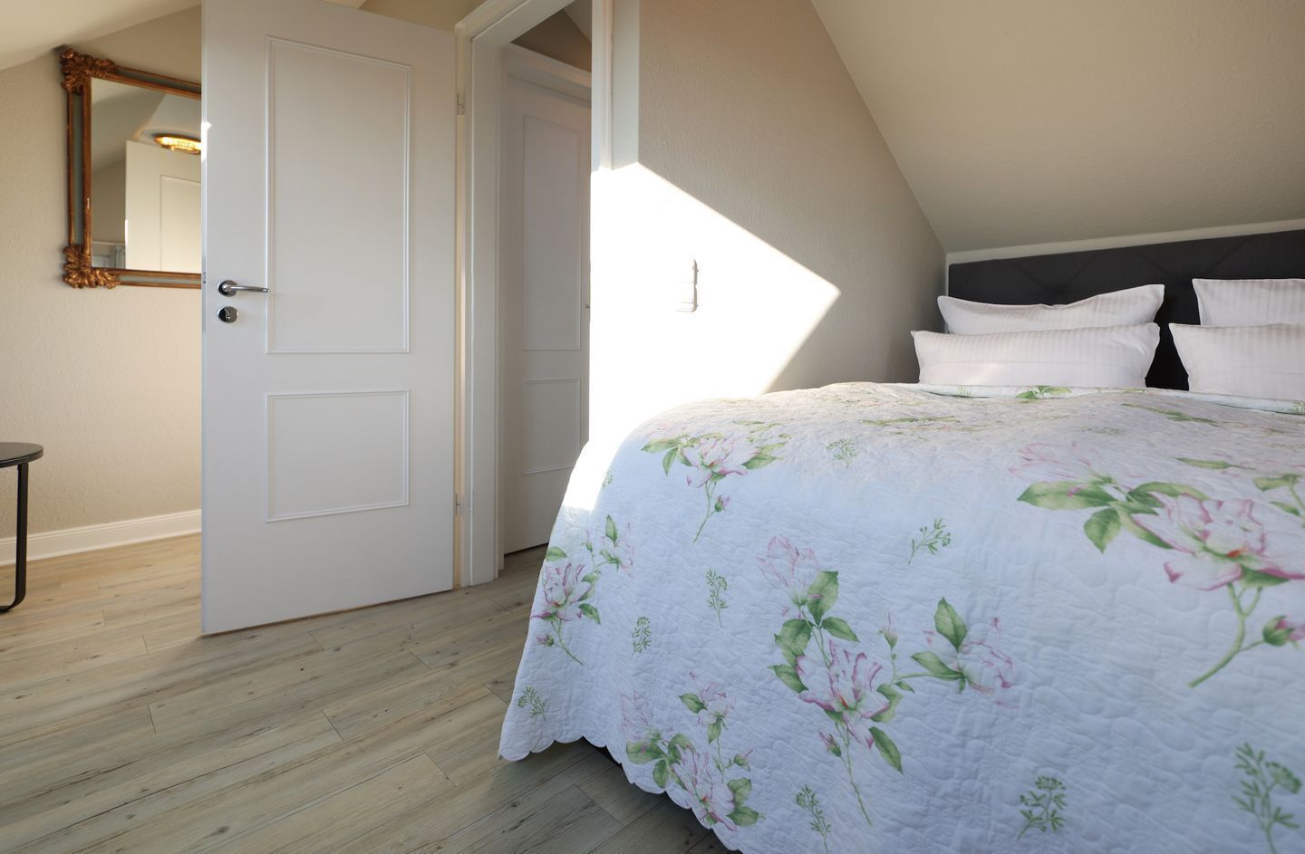 A bedroom with a bed, a door, and a mirror.