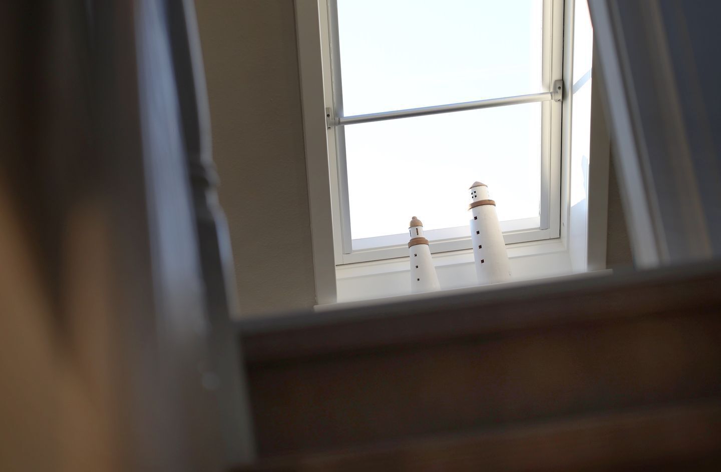 Una ventana con dos faros blancos sobre el alféizar.