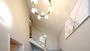A modern staircase with a circular light fixture and a wall-mounted abstract art piece. - Bright vacation apartment in a central location close to the beach in Westerland. - Beach villa (Sylt)