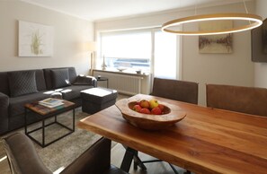 Ett modernt vardagsrum med ett matbord i trä, en grå soffa och ett soffbord.