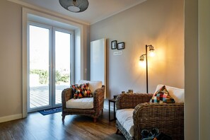 Una habitación con dos sofás de mimbre, una mesita, una lámpara de pie y un cartel que indica una 'ZONA DE RELAX'.