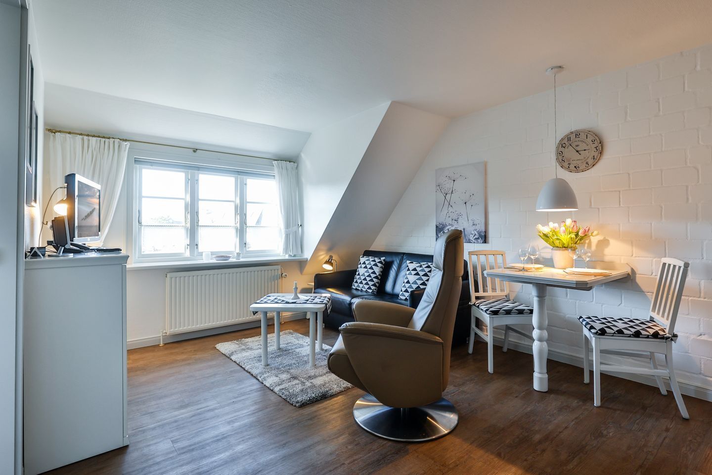 A modern loft apartment with a dining area, a sofa with geometric cushions, and a dining table with chairs.