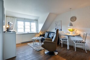 A modern loft apartment with a dining area, a sofa with geometric cushions, and a dining table with chairs.