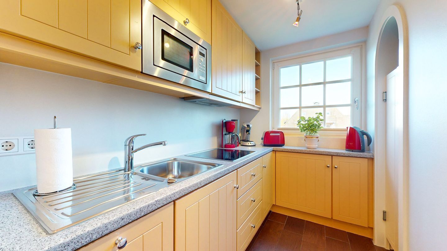 A modern kitchen with stainless steel appliances, a double sink, and wooden cabinets.