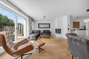 A modern living room with a sofa, chairs, and a fireplace.