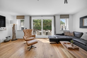 A modern living room with a leather sofa, a tufted armchair, and a wooden coffee table.
