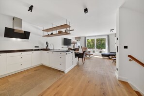 A modern kitchen with white cabinets, a wooden countertop, and a built-in oven.