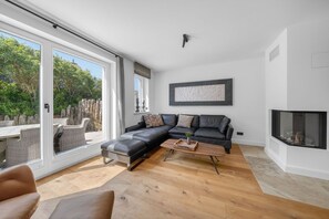A modern living room with a black leather sofa, a wooden coffee table, and a fireplace.