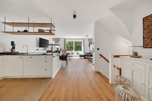 A spacious kitchen with a central island, a dining area with a chair, and a view of a balcony.