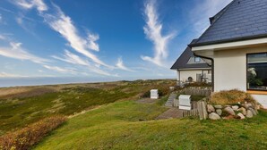 Ein Haus mit geneigtem Dach, einer kleinen Veranda und Blick auf das Meer.