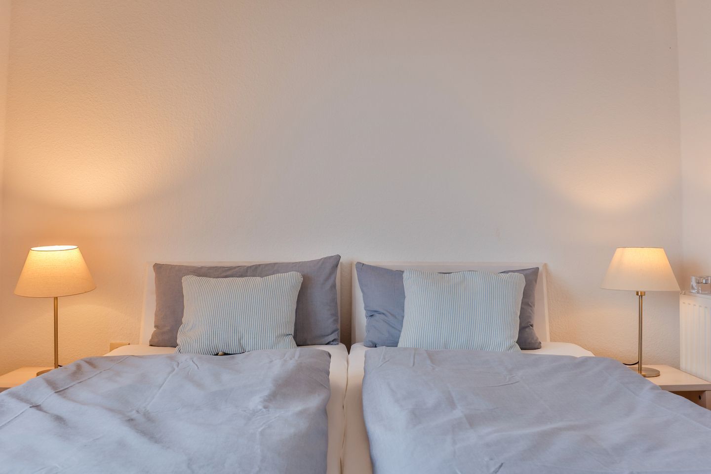 Una cama doble con dos almohadas, una mesita de noche y una lámpara a cada lado.