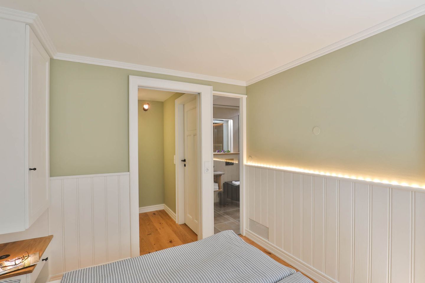 A bedroom with a bed, a dresser, and a door leading to a bathroom.
