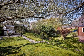 Un jardin résidentiel agrémenté d’un chemin en pierre, d’une pergola en bois et d’une maison en briques.