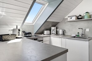 A modern kitchen with a skylight, built-in appliances, and a minimalist design.